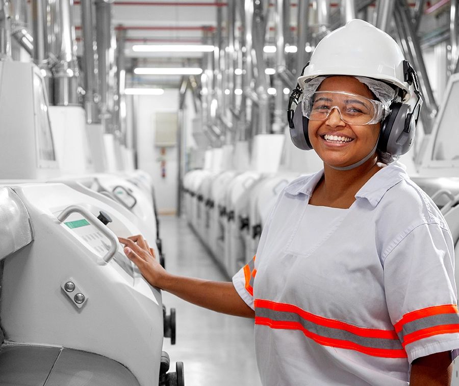 Fotografia industrial — operadora na linha de produção de soja — Operadora com capacete, óculos e protetor auricular no painel de controle da linha, na unidade da Bunge em Luís Eduardo Magalhães, Bahia.