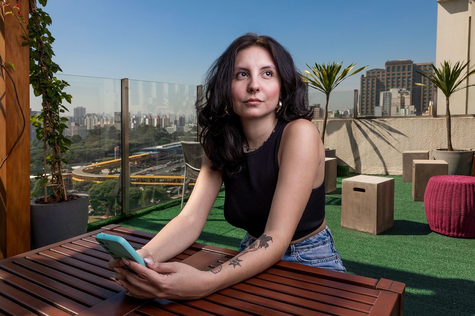 Fotografia institucional — colaboradora à mesa no escritório da Tenda — Colaboradora sentada à mesa com o celular, no escritório da Tenda Construtora. Uso institucional.