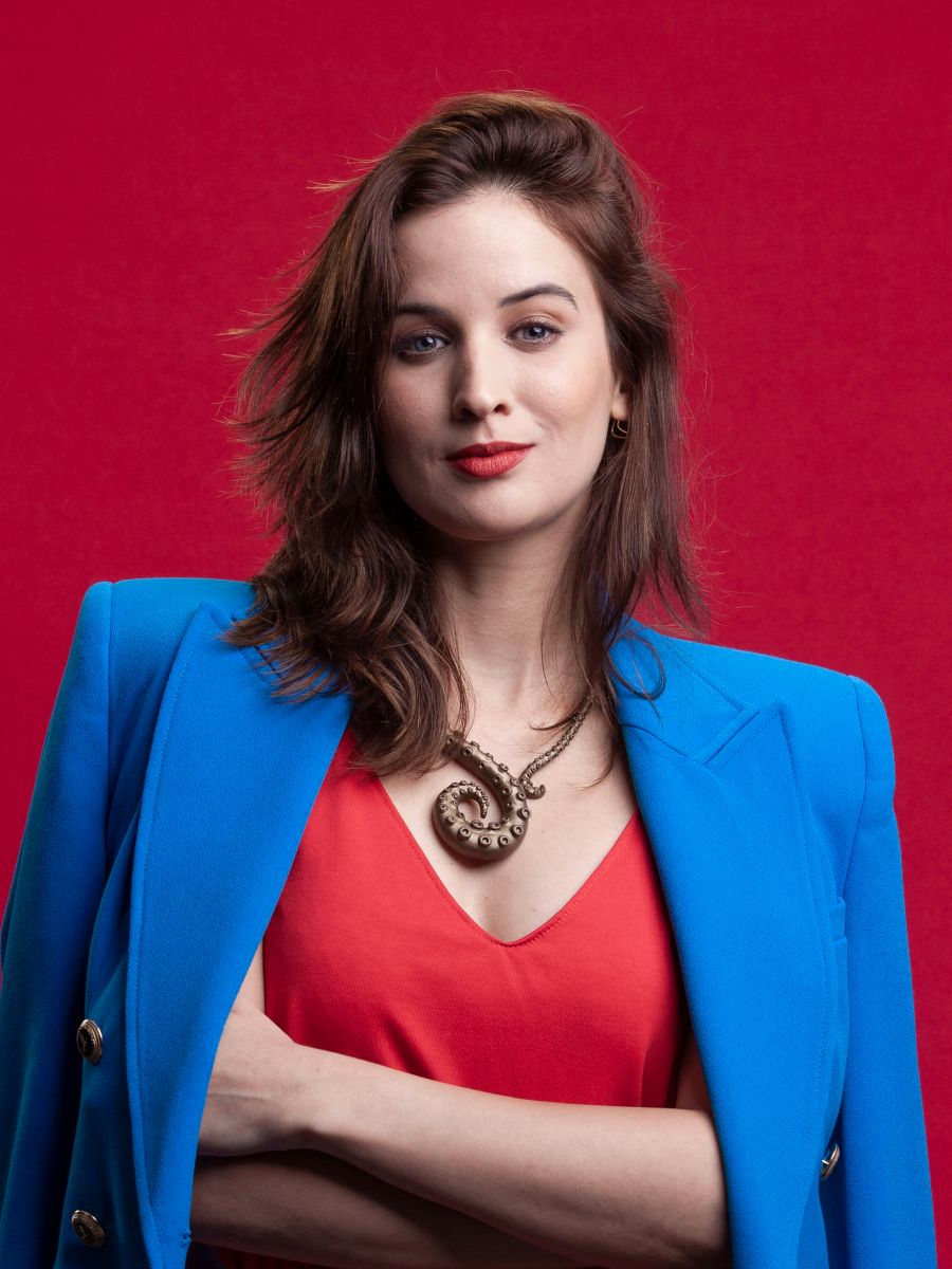 Retrato executivo feminino em estúdio — Executiva em blazer azul sobre fundo vermelho, em estúdio no Alto da Lapa, São Paulo. Luz suave que desenha o maxilar, feito para posicionamento no LinkedIn.