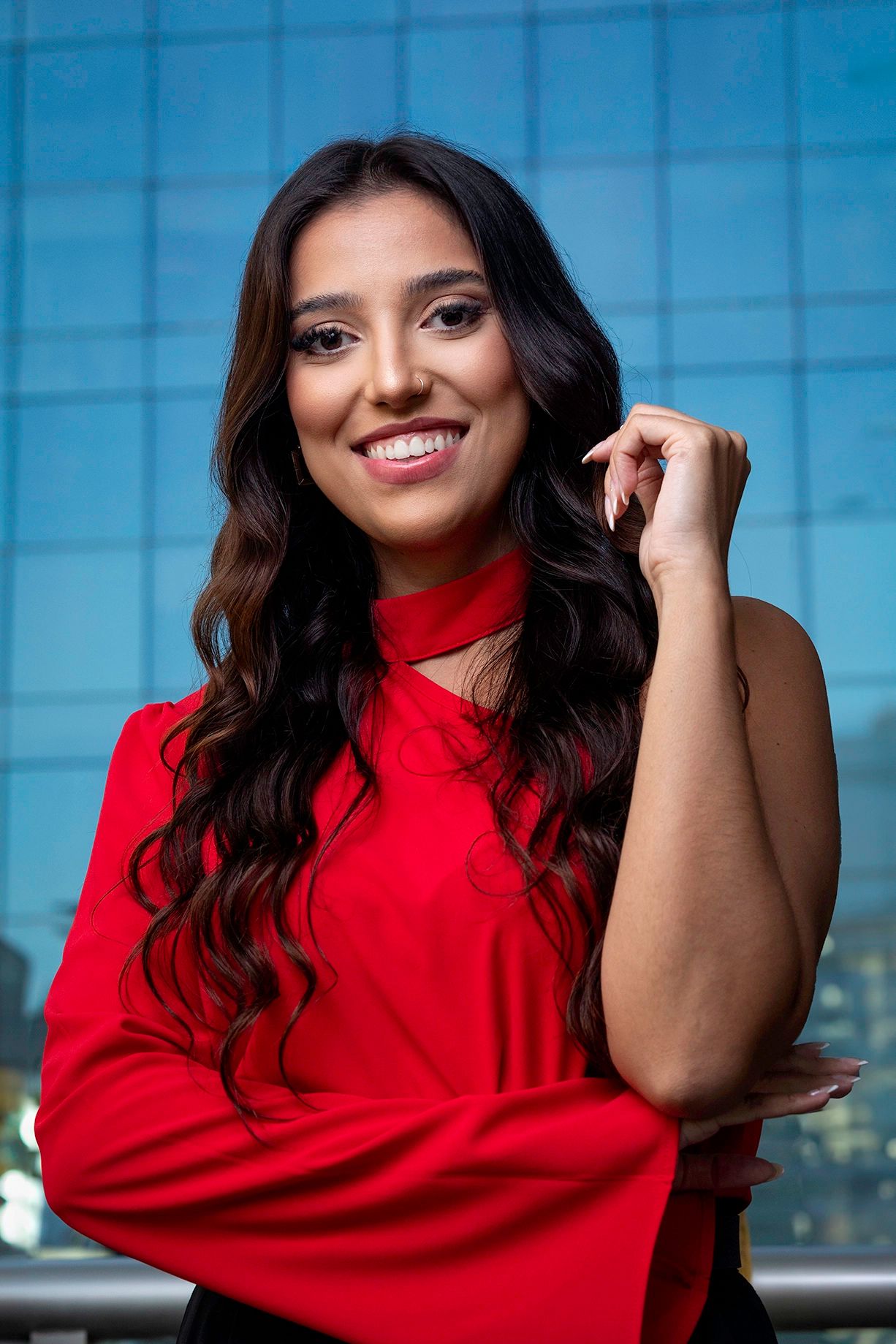 Retrato executivo feminino in loco — Advogada com camisa vermelha e fundo azul, no escritório dela em São Paulo. Luz suave e contraste cromático, feito para posicionamento no LinkedIn.