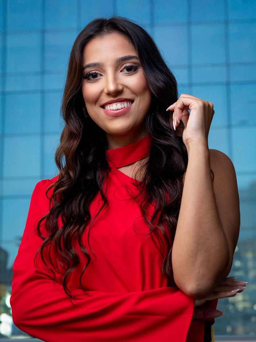 Retrato executivo feminino in loco — Advogada com camisa vermelha e fundo azul, no escritório dela em São Paulo. Luz suave e contraste cromático, feito para posicionamento no LinkedIn.